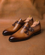 Side profile of a tan and brown tassel monk strap on a leather sole